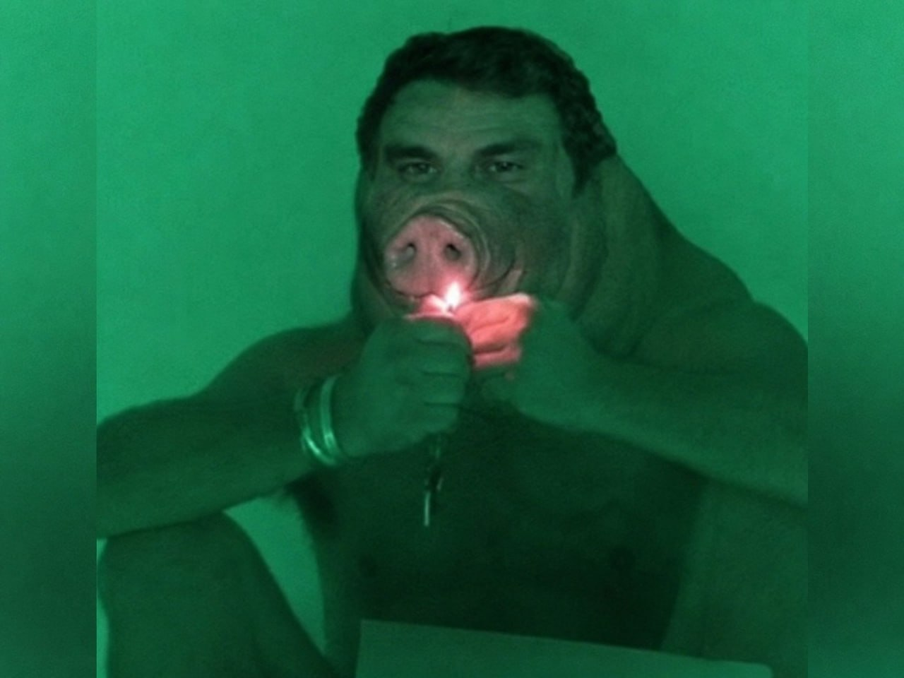 Green-tinted pig-faced figure lighting a match